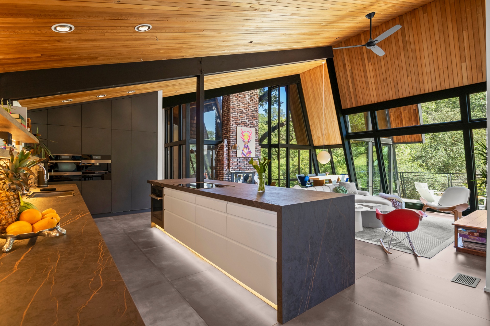 Open kitchen and living space with a marble island and red accent chairs