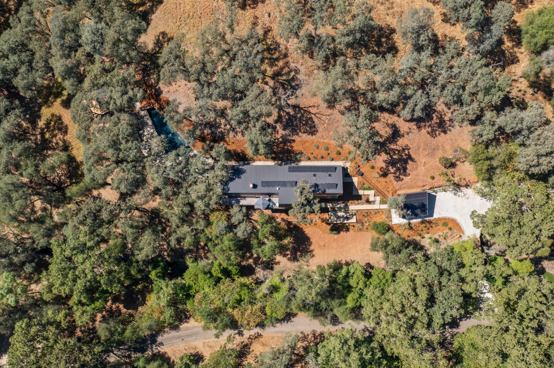 High overhead aerial showing the full property and driveway surrounded by oak woodland