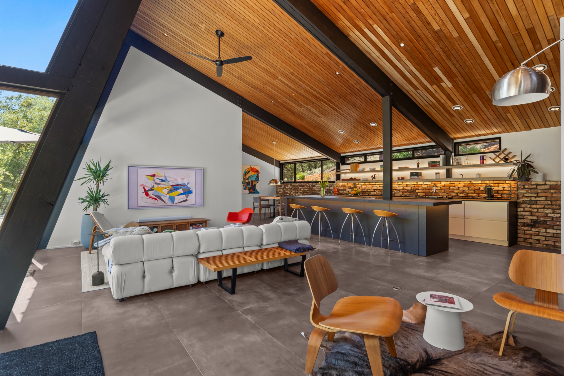 Open-plan living room and bar with vaulted wood ceiling and abstract art