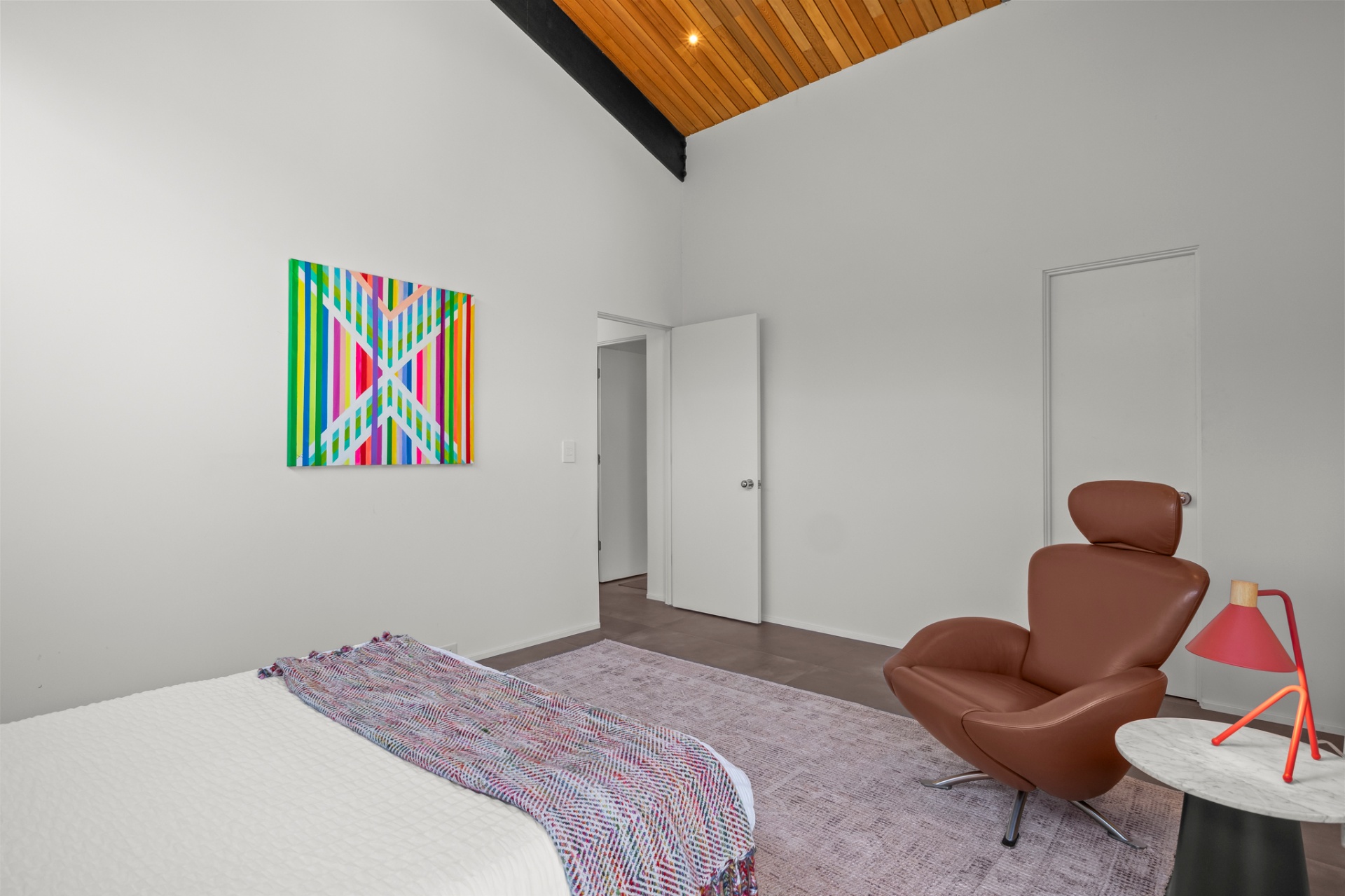 Bedroom corner with leather lounge chair, red lamp and striped canvas