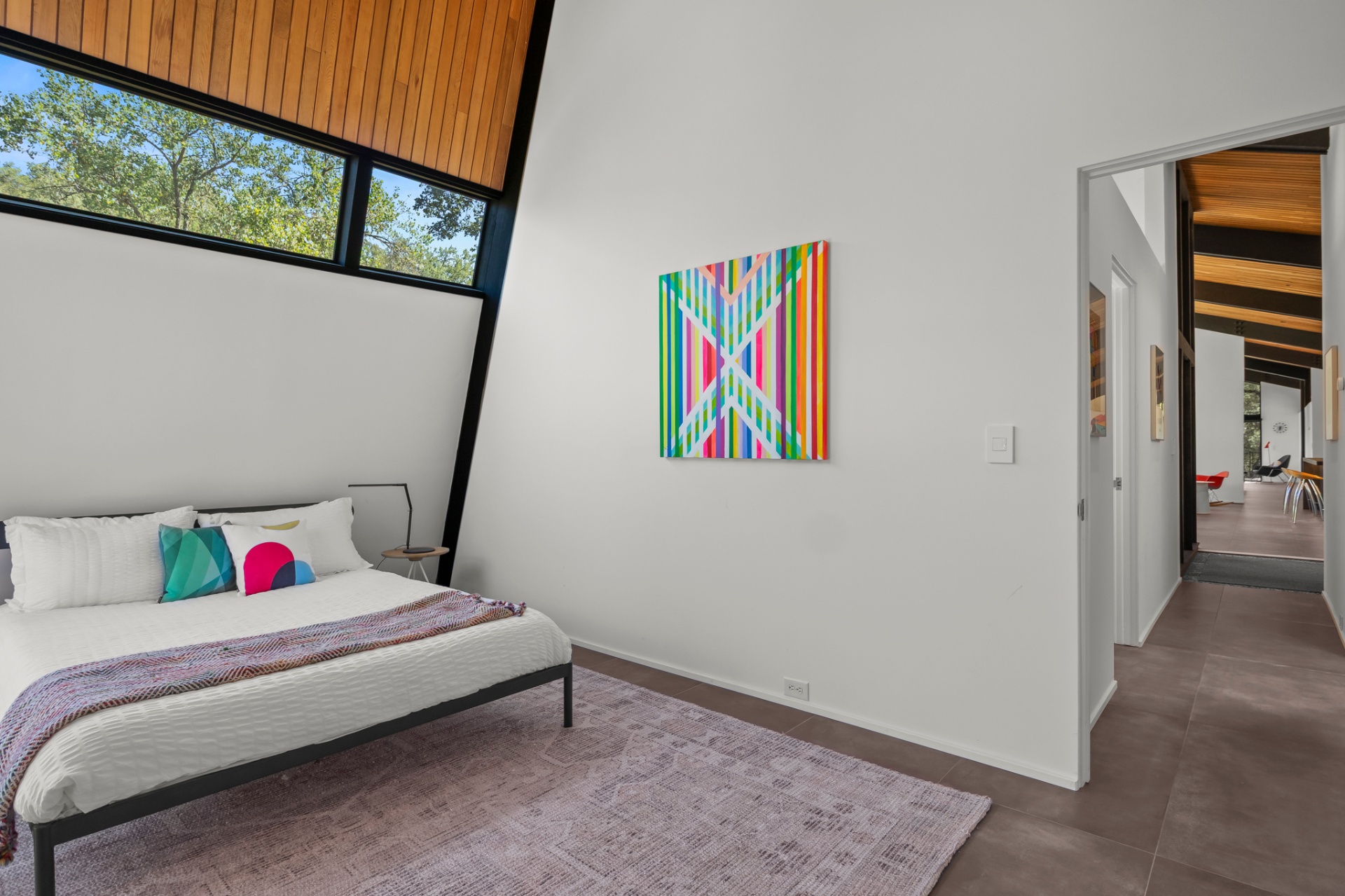 Guest bedroom with striped color-field painting and clerestory windows