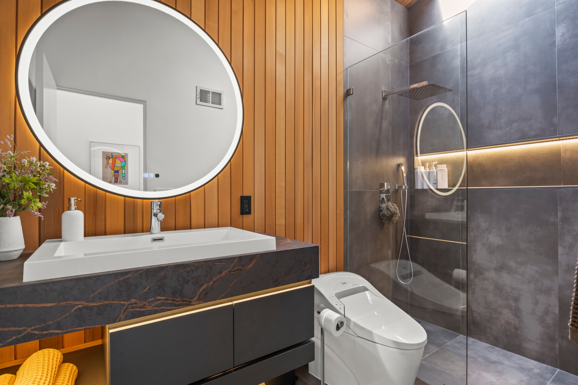 Secondary bath with backlit round mirror, cedar wall and glass shower
