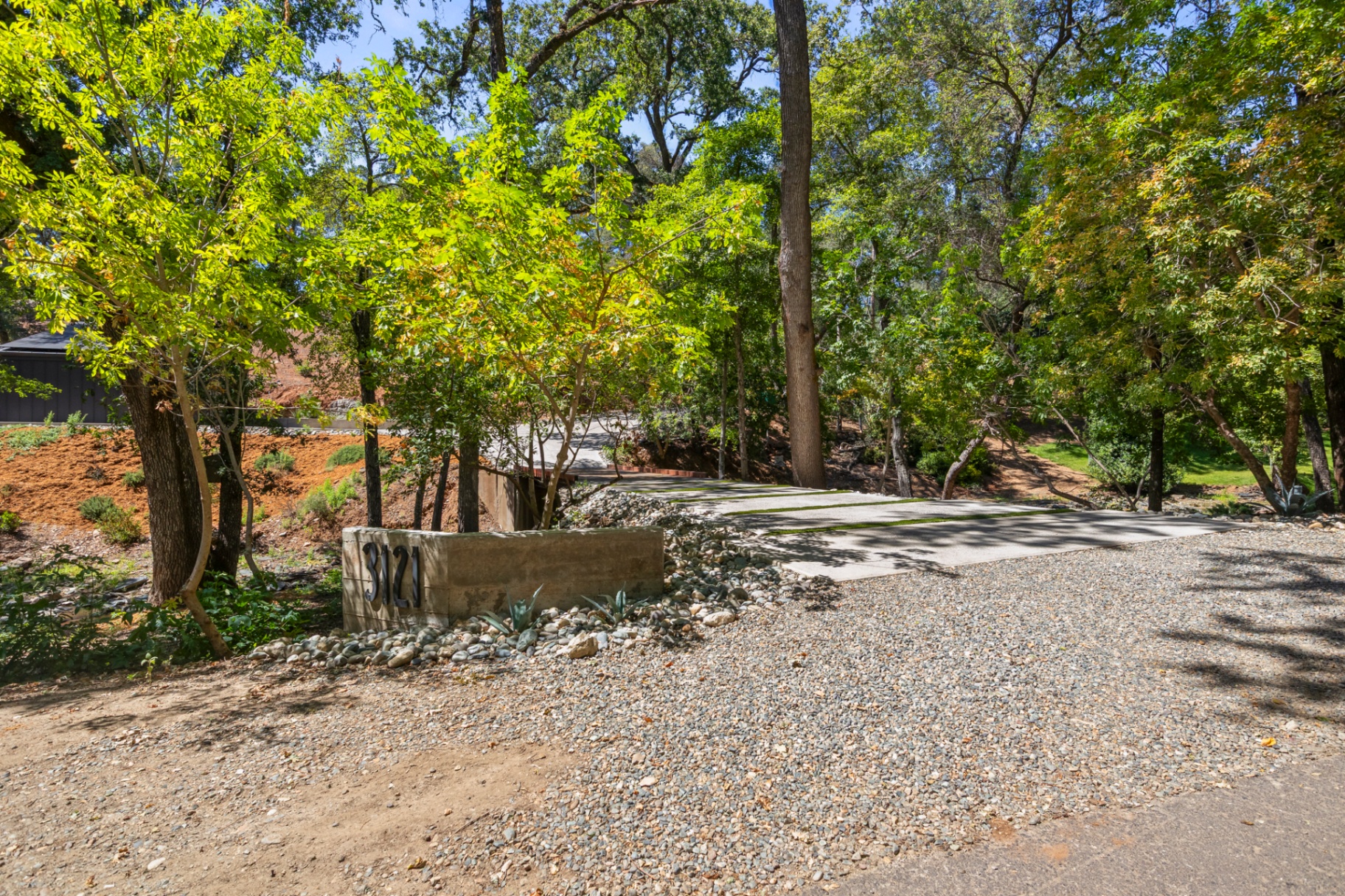 Driveway entrance with the 3121 property marker among the trees