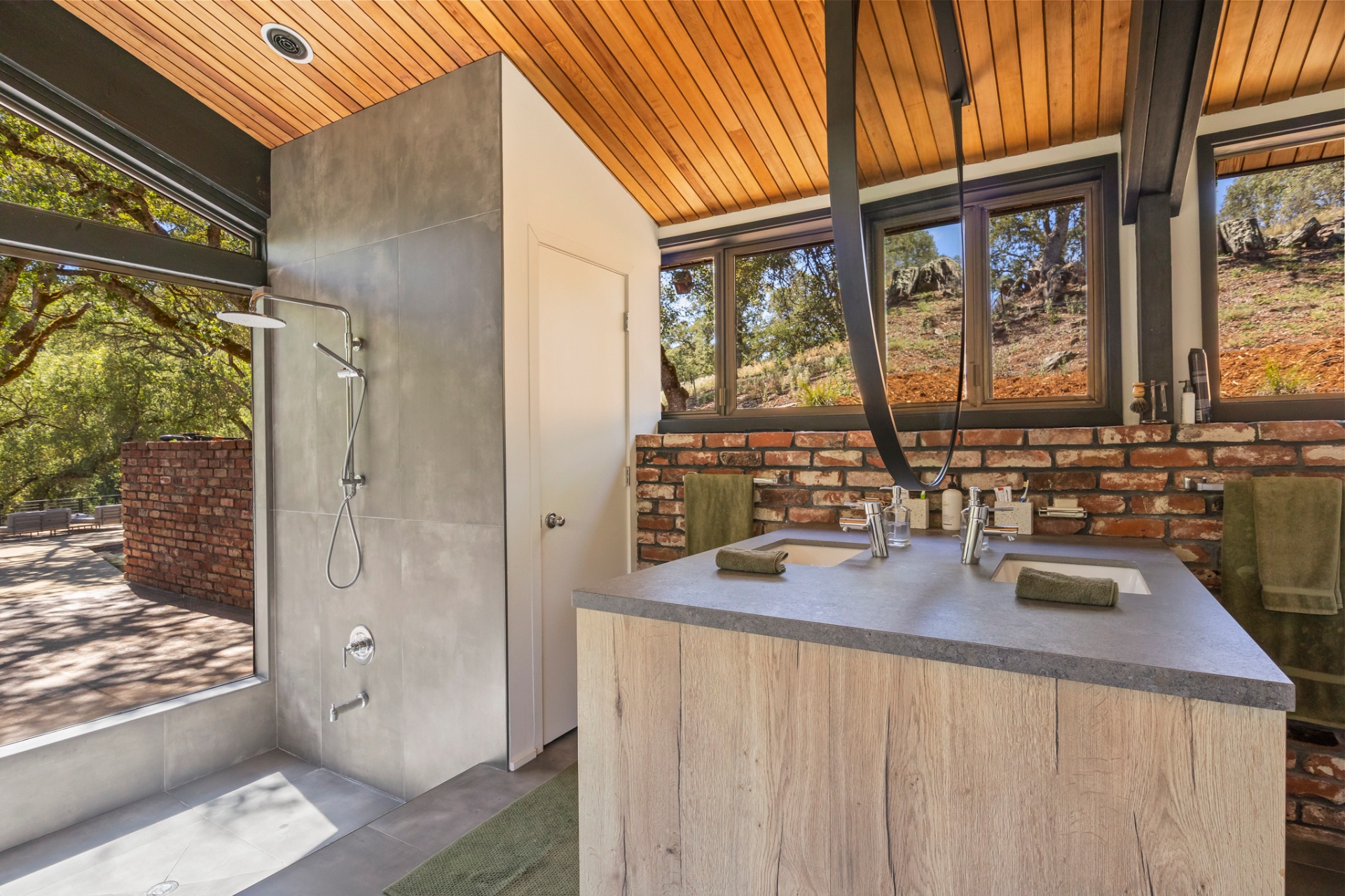 Primary bath with walk-in concrete-look tile and Dekton shower and brick wall
