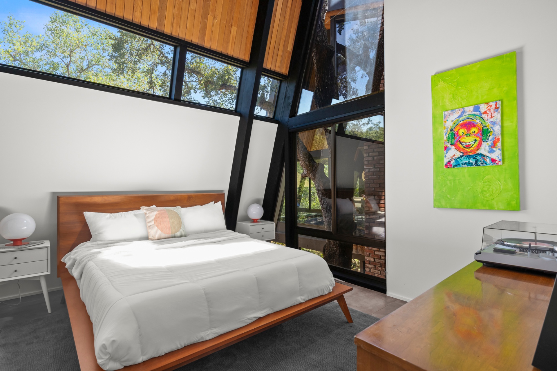 Guest bedroom with platform bed, wall of windows and green portrait