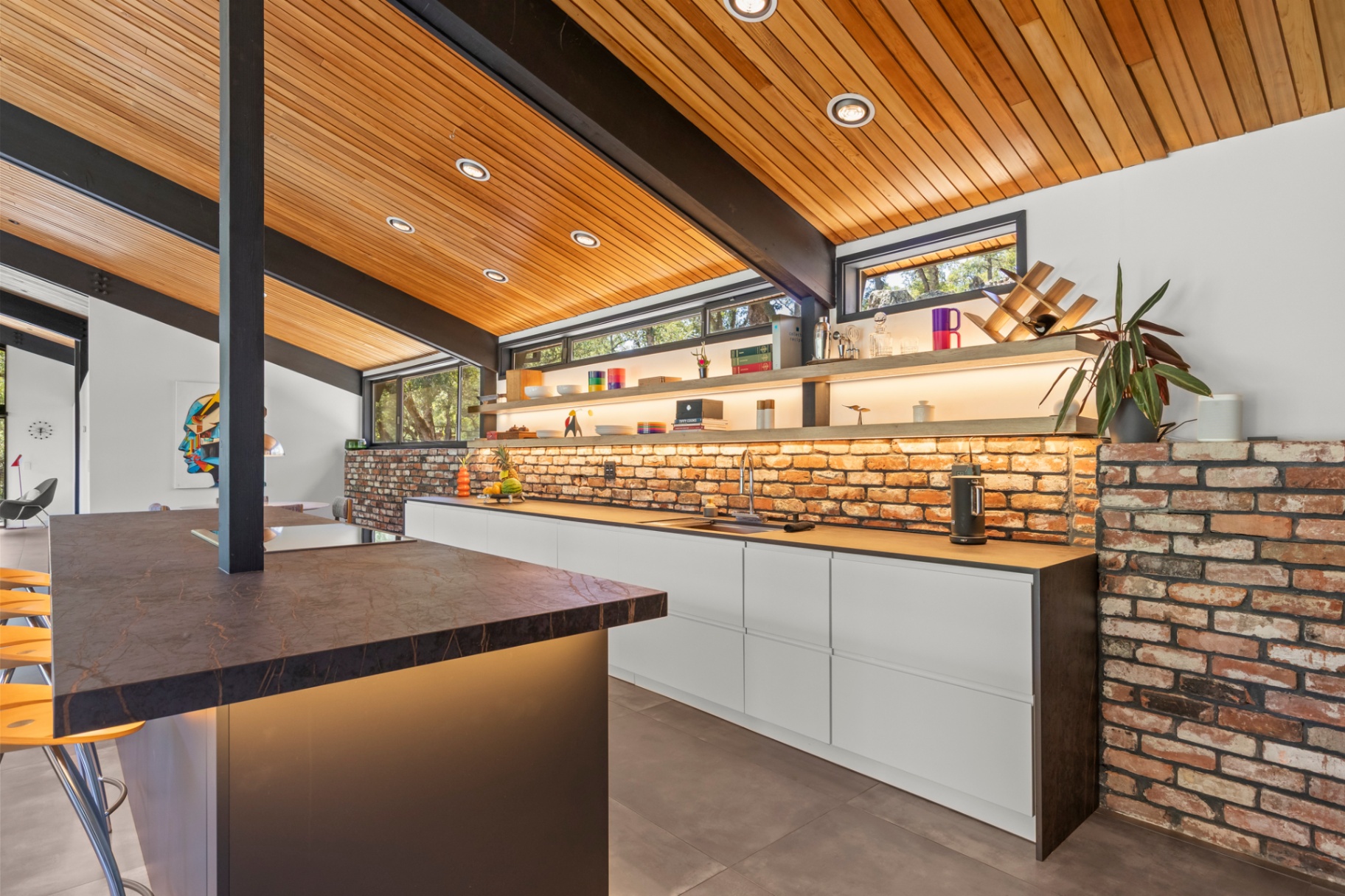 Kitchen with brick backsplash, floating shelves and a concrete island