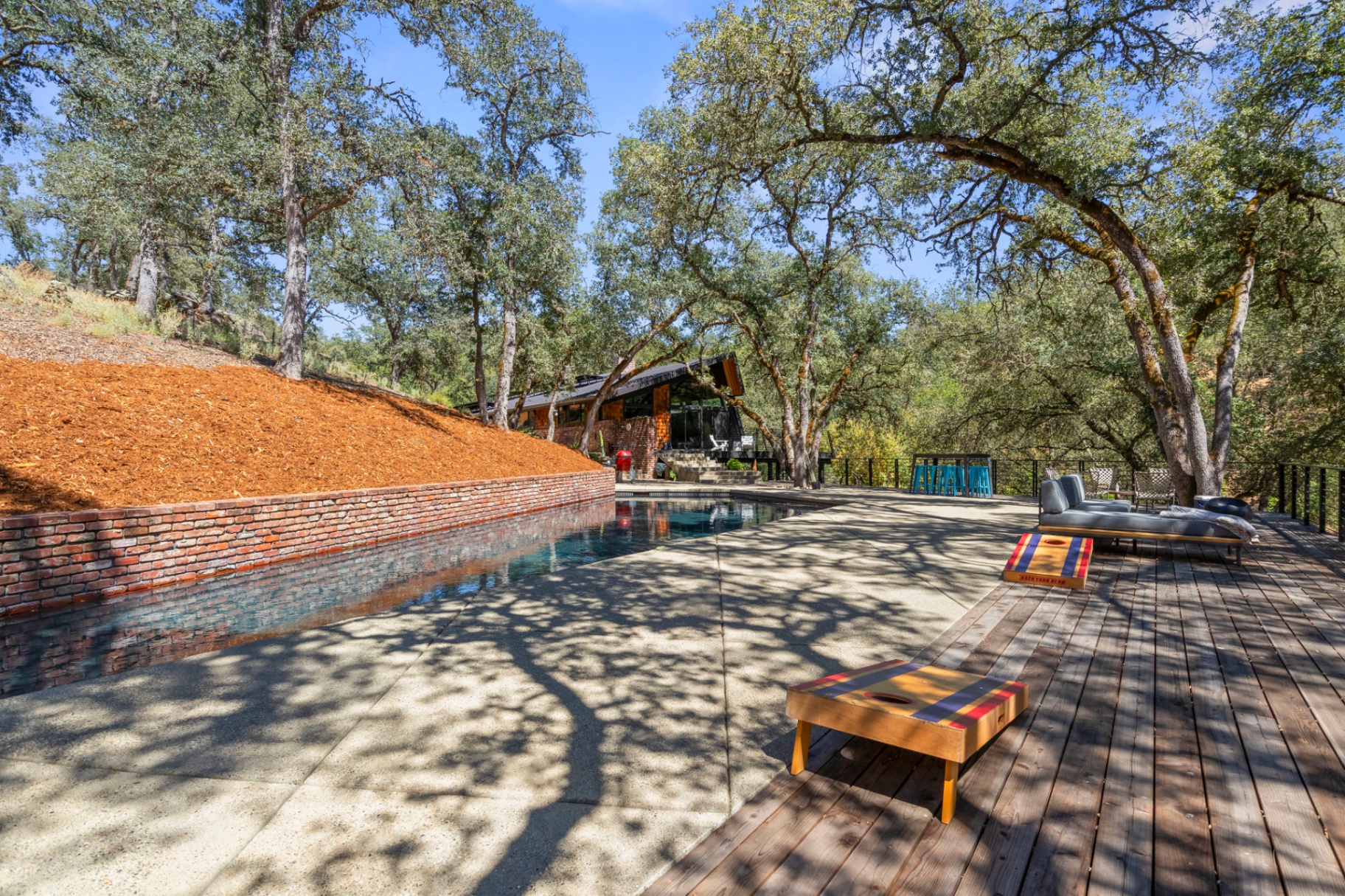 Pool deck and patio with lounge chairs and cornhole