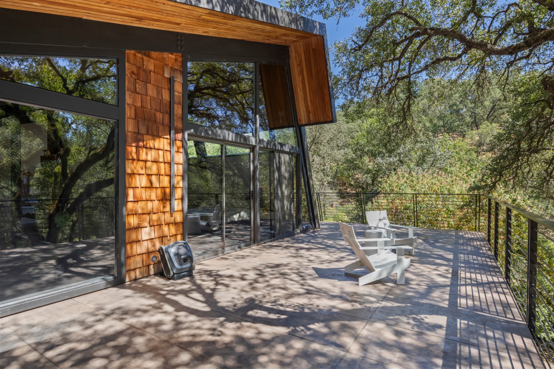 Concrete patio and deck beside the cedar-shingle wall with white Adirondack chairs