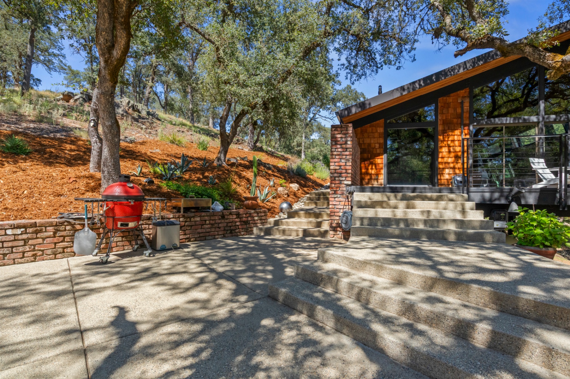 Patio and steps with a kamado grill and the home's shingled exterior