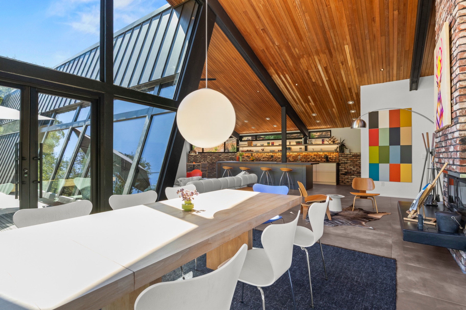Dramatic A-frame dining room with wood ceiling, globe pendant and color-block art
