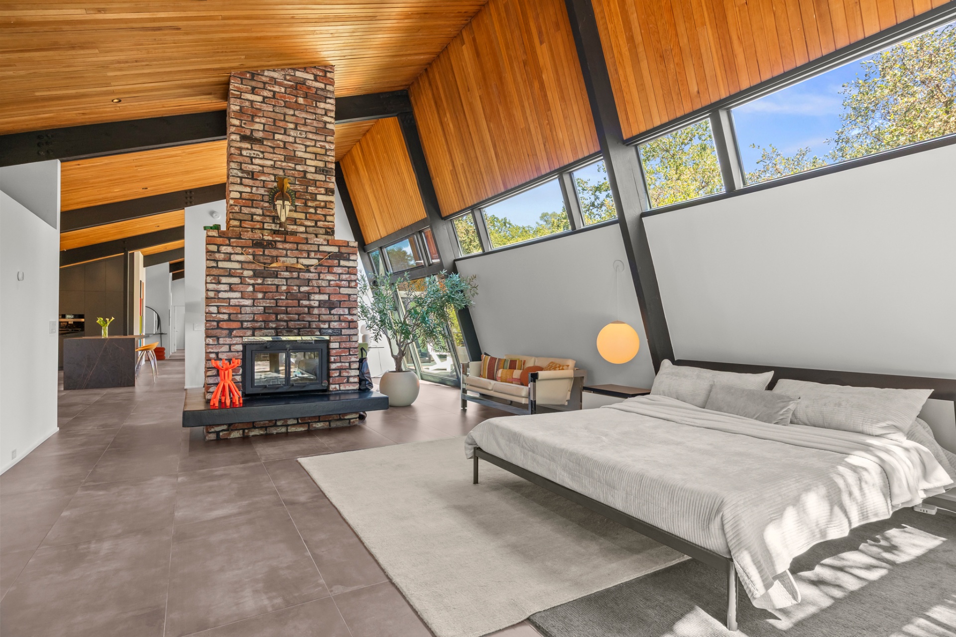 Primary bedroom with two-sided brick fireplace and vaulted wood ceiling