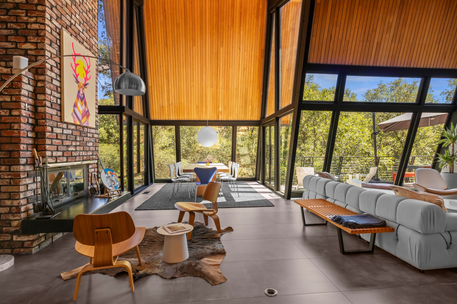 Living room with brick fireplace, modern art and full-height window walls